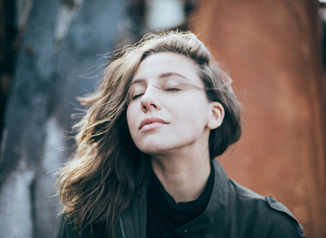 Frau mit geschlossenen Augen und wehendem Haar.