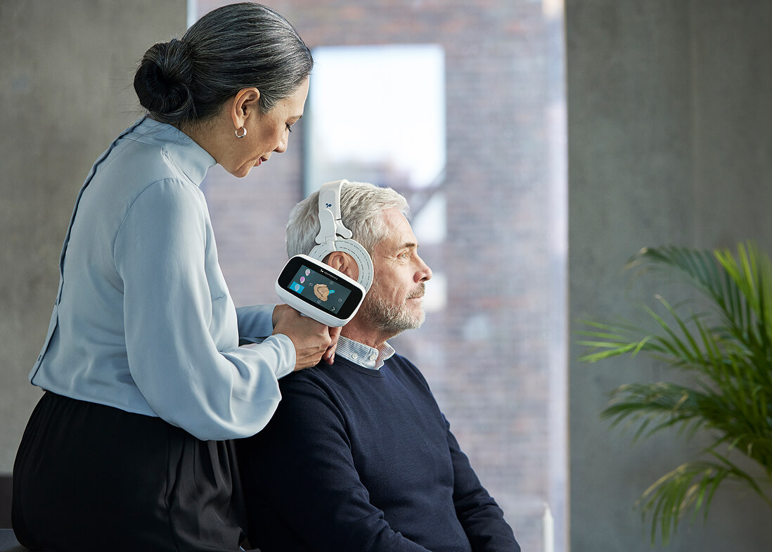 Frau misst Gehör bei Mann mit Spezialgerät.