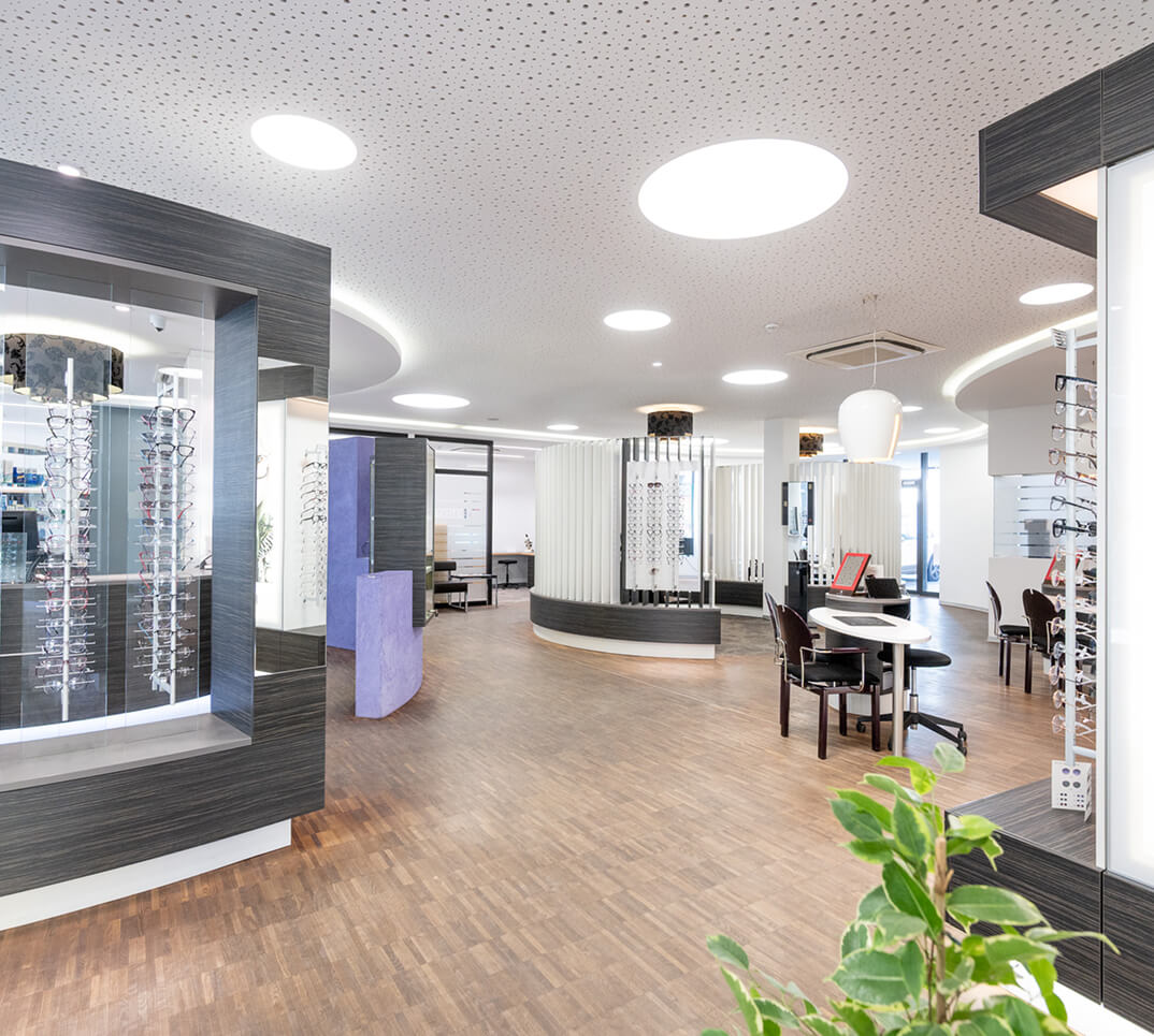 Heller Optikerladen mit Brillendisplays und Sitzbereichen.