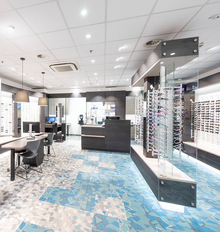 Helles Optikergeschäft mit Brillenständern und Tischen.