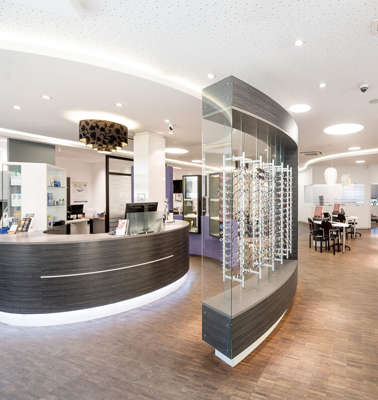 Moderner Optikerladen mit Empfang und Brillenständern.