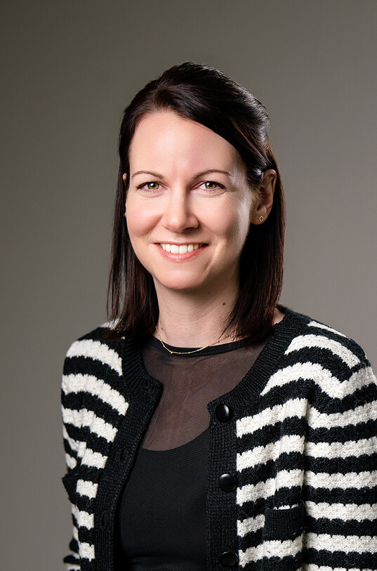 Frau lächelt, trägt gestreifte Strickjacke.