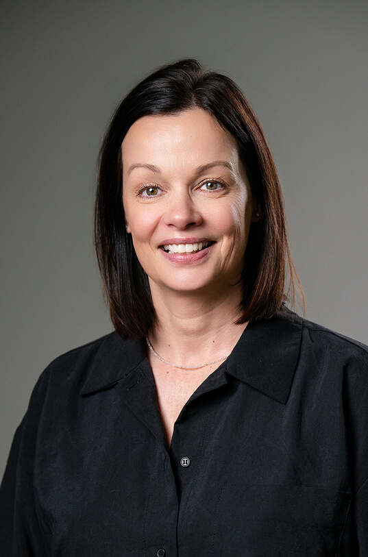 Lächelnde Frau mit schulterlangem Haar und schwarzem Hemd.