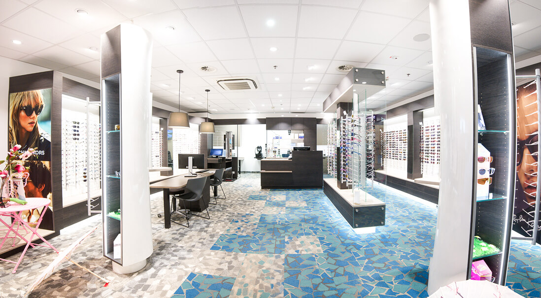 Heller Optikerladen mit Brillen, Theke und blauem Boden.