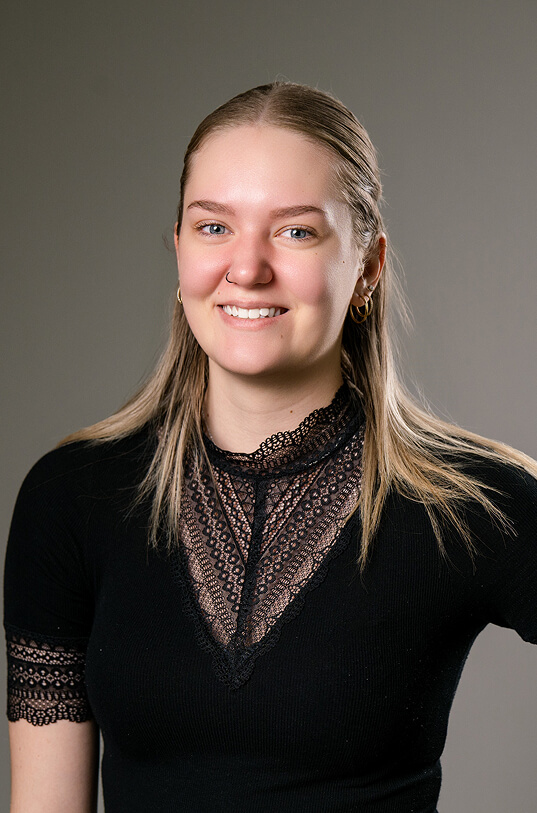 Lachende Frau, blaue Augen, Piercings, schwarzes Spitzentop.